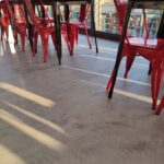 Sedie rosse in fila vicino a vetrata soleggiata.