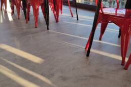 Sedie rosse in fila vicino a vetrata soleggiata.