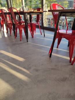 Sedie rosse in fila vicino a vetrata soleggiata.