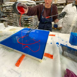 Persona versa pittura rossa su tela blu.